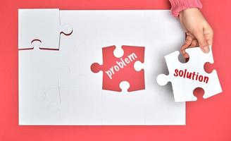 female hand holding white puzzle with the word solution, process of closing the missing element with the word problem photo