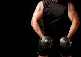 man in black clothes holds steel dumbbells in his hands photo