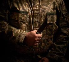 soldado vestido con uniforme militar sostiene un cuchillo táctico afilado