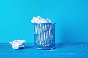 blue metal bucket filled with crumpled white paper photo