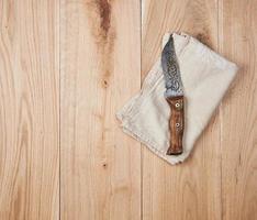 old knife and dishcloth on a wooden background photo