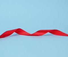 red silk thin ribbon twisted on a blue background photo