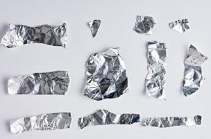 various pieces of silver foil on a white background photo