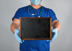 doctor in blue uniform and sterile latex gloves holding a wooden frame photo