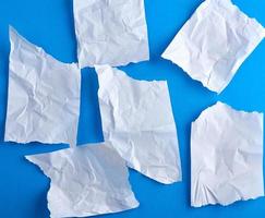 crumpled empty torn pieces of white paper on a blue background photo