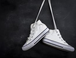 pairs of used textile shoes hang on a black background photo