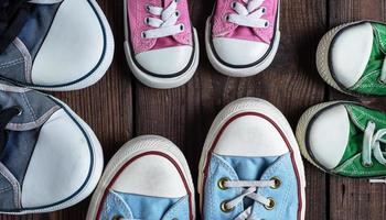 four pairs of old textile sneakers on a black background photo