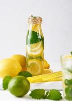 summer refreshing drink lemonade with lemons, mint leaves, lime in a glass bottle photo