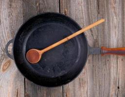 cuchara de madera y sartén redonda negra vacía con mango de madera foto