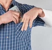 el hombre con una camisa azul pone en un bolsillo una pila de papel moneda foto