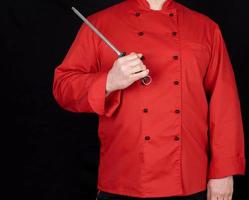 chef in red uniform holds knife sharpening tool photo