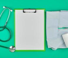 empty white sheets and a medical stethoscope on a green background photo