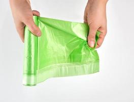 female hand unwind green roll with plastic bags for garbage photo