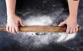 very old brown wooden rolling pin in female hands photo