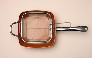 empty copper deep frying pan with grill grate on beige background. View from above photo