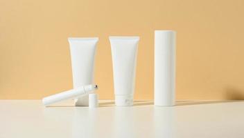 empty white plastic tube, thin roller, bottle on a beige background. Cosmetic products for branding gel, cream, lotion, shampoo. Mock up eco cosmetics photo