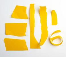 various torn strips of yellow paper on a white background photo