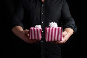 adult man in a black shirt holds in his hand a stack of paper-wrapped gifts photo
