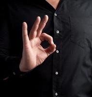 el hombre con una camisa negra muestra el símbolo ok con la mano derecha foto