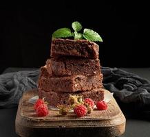 stack of baked square pieces of chocolate brownie cake on brown wooden cutting board photo