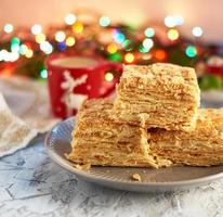 stack of slices of Napoleon cake made of puff pastry and butter cream in a gray ceramic plate photo