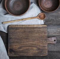empty old cutting board, spoon and two empty clay bowls photo