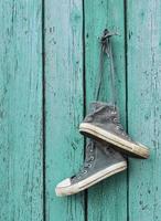 pair of very worn black textile sneakers hang on a nail photo