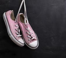 pair of pink textile sneakers hanging on a lace photo