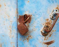 old rusty lock hanging on a blue metal door photo