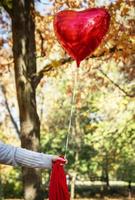 female hand holding a red balloon photo