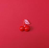 Red plastic childrens toy cherry on a red background photo