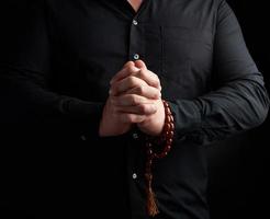 man in a black shirt joined his hands in front of his chest, prayer pose photo