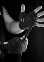 man wraps his hands in black textile bandage for sports photo