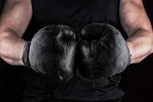 hands of an athlete in black old sport boxing gloves photo