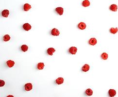 red ripe raspberries scattered on a white background, top view photo