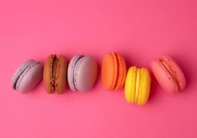 colorful baked macarons almond flour on a pink background photo