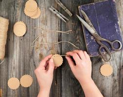 dos manos femeninas y etiquetas de papel con una cuerda marrón sobre una mesa de madera gris foto