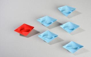 group of paper boats on a gray background. concept of a strong leader in a team, manipulation photo