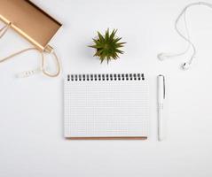 spiral notebook with empty sheets, pen and green plants photo