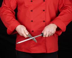 chef in red uniform sharpens a knife photo