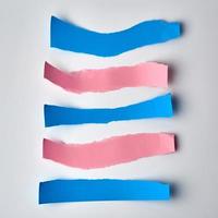 pink and blue torn strips of paper on a white background photo