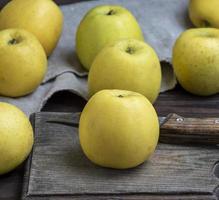 ripe whole yellow apples on a brown wooden board photo