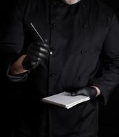 chef in black uniform and gloves is holding a blank notebook photo