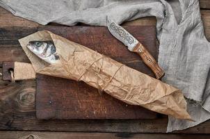 Fresh whole sea bass fish wrapped in a brown paper photo