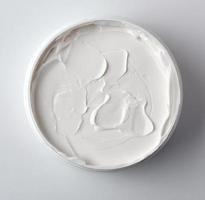 thick white cosmetic cream in a plastic jar, top view photo