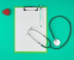 empty white sheets and a medical stethoscope on a green background photo