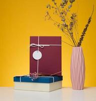 A stack of gift boxes wrapped in colorful paper on a yellow background. Happy Holidays photo