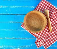 empty round wooden plate and spoon on a red-white textile napkin photo