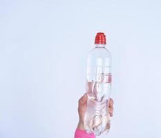 botella de plástico transparente con agua dulce en una mano femenina foto