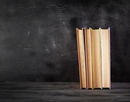 four closed books with yellow sheets on a black chalk board background photo